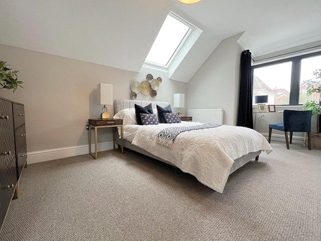 A bedroom with a large bed and a skylight on the ceiling.
