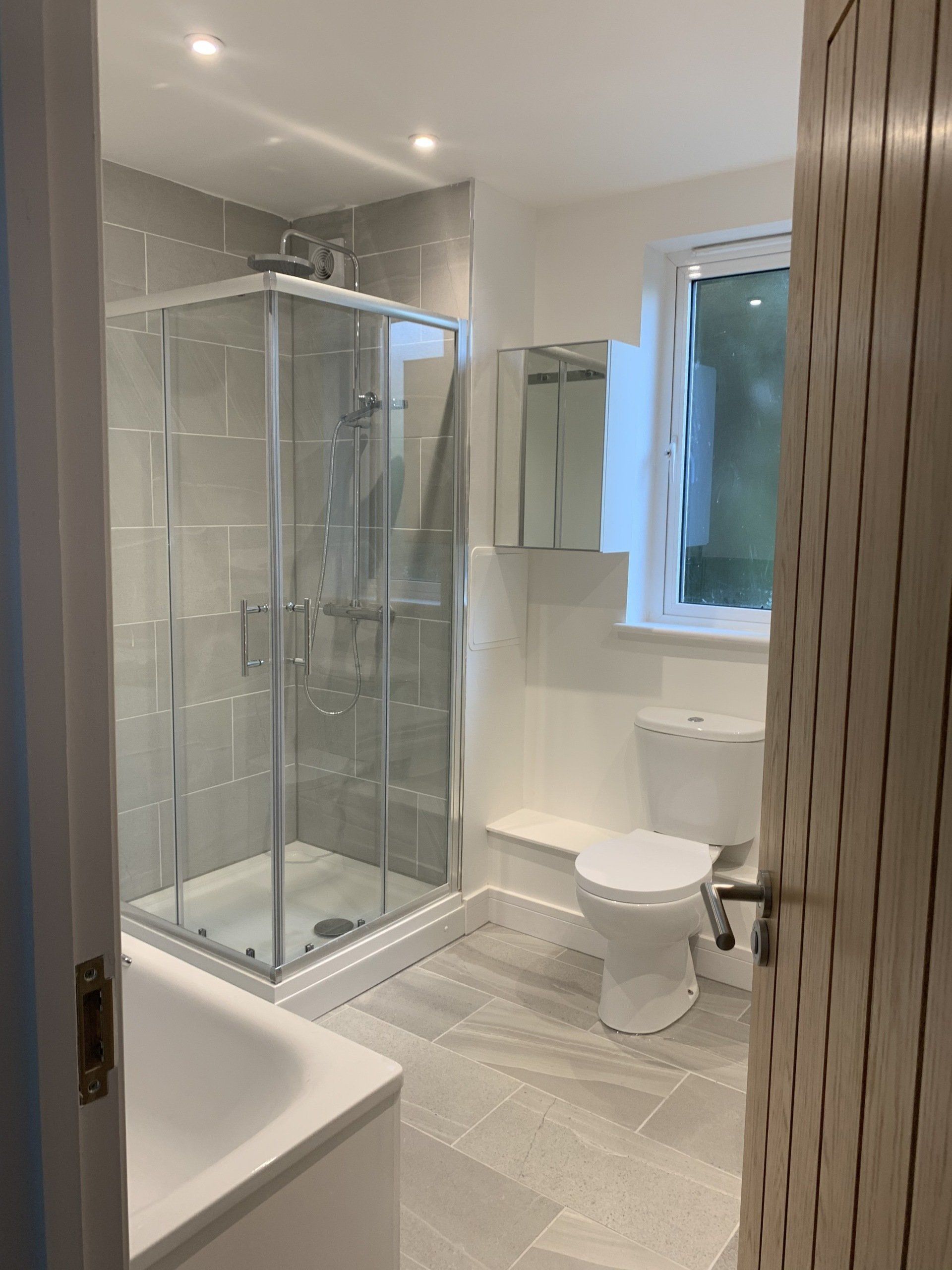 A bathroom with a toilet , shower , tub and mirror.