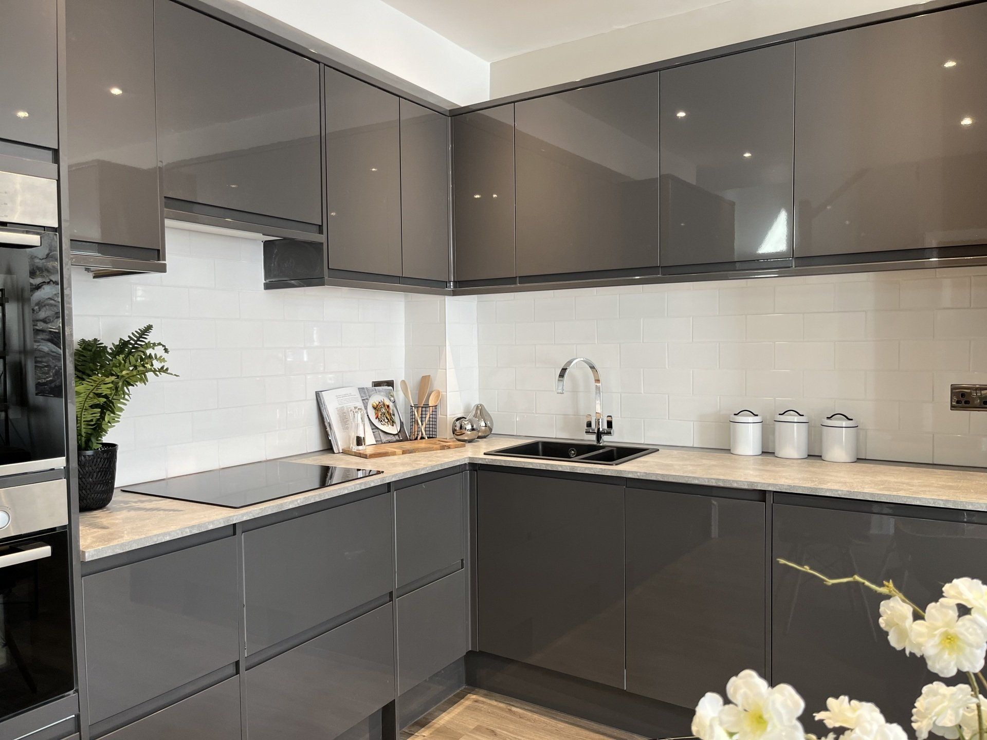 A kitchen with gray cabinets , a sink , and a stove top oven.