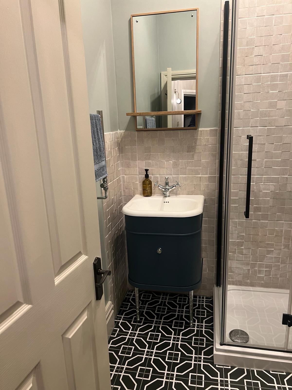 A bathroom with a sink , mirror and shower.
