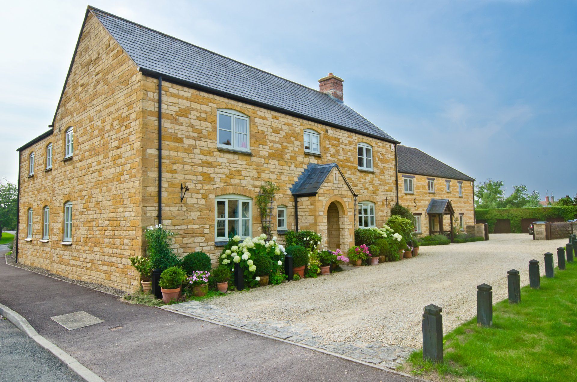 A large stone house with a gravel driveway in front of it