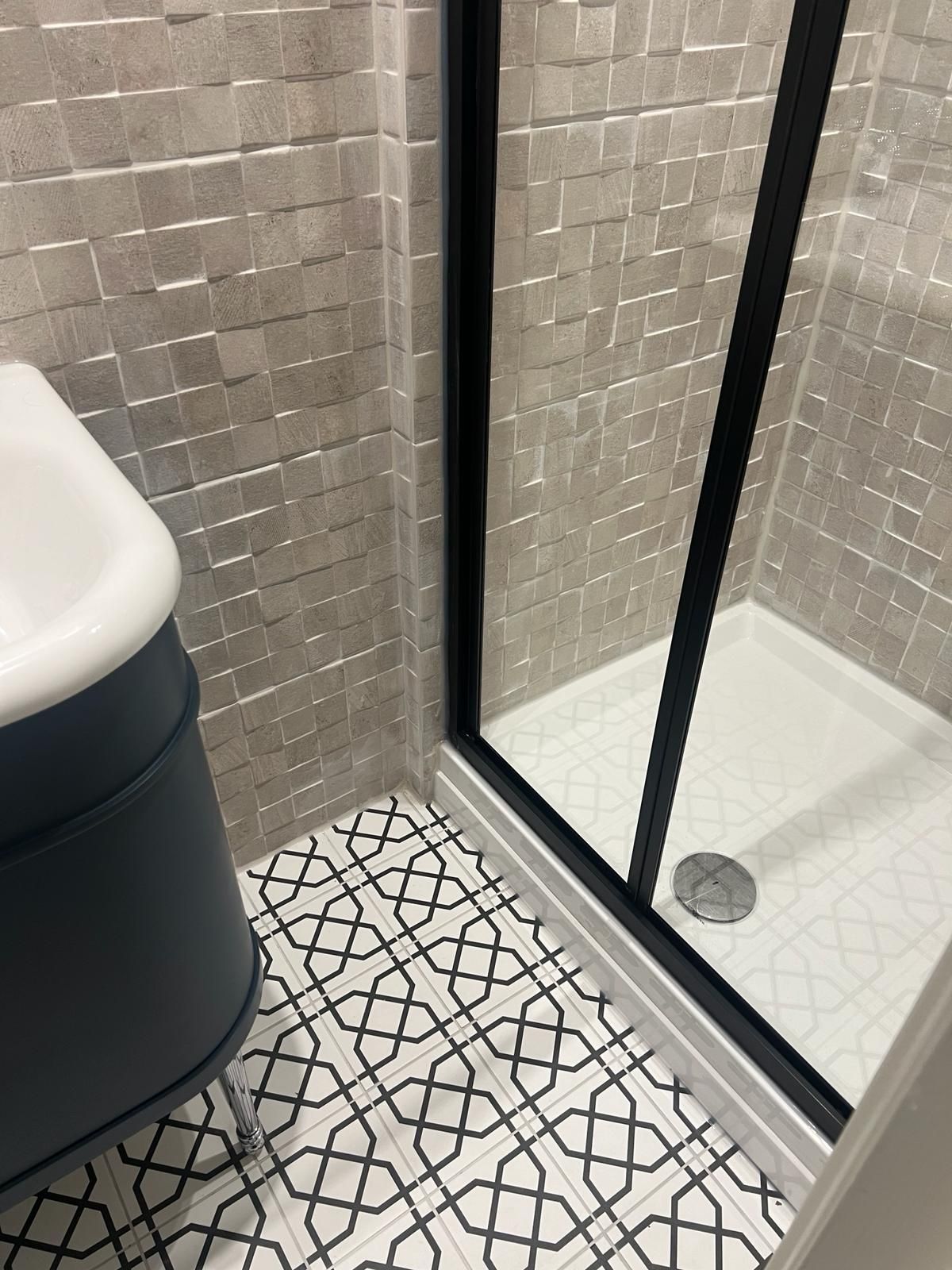 A bathroom with a walk in shower and a sink