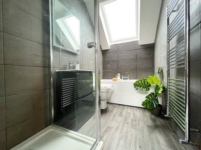 A bathroom with a walk in shower , bathtub , toilet and skylight.