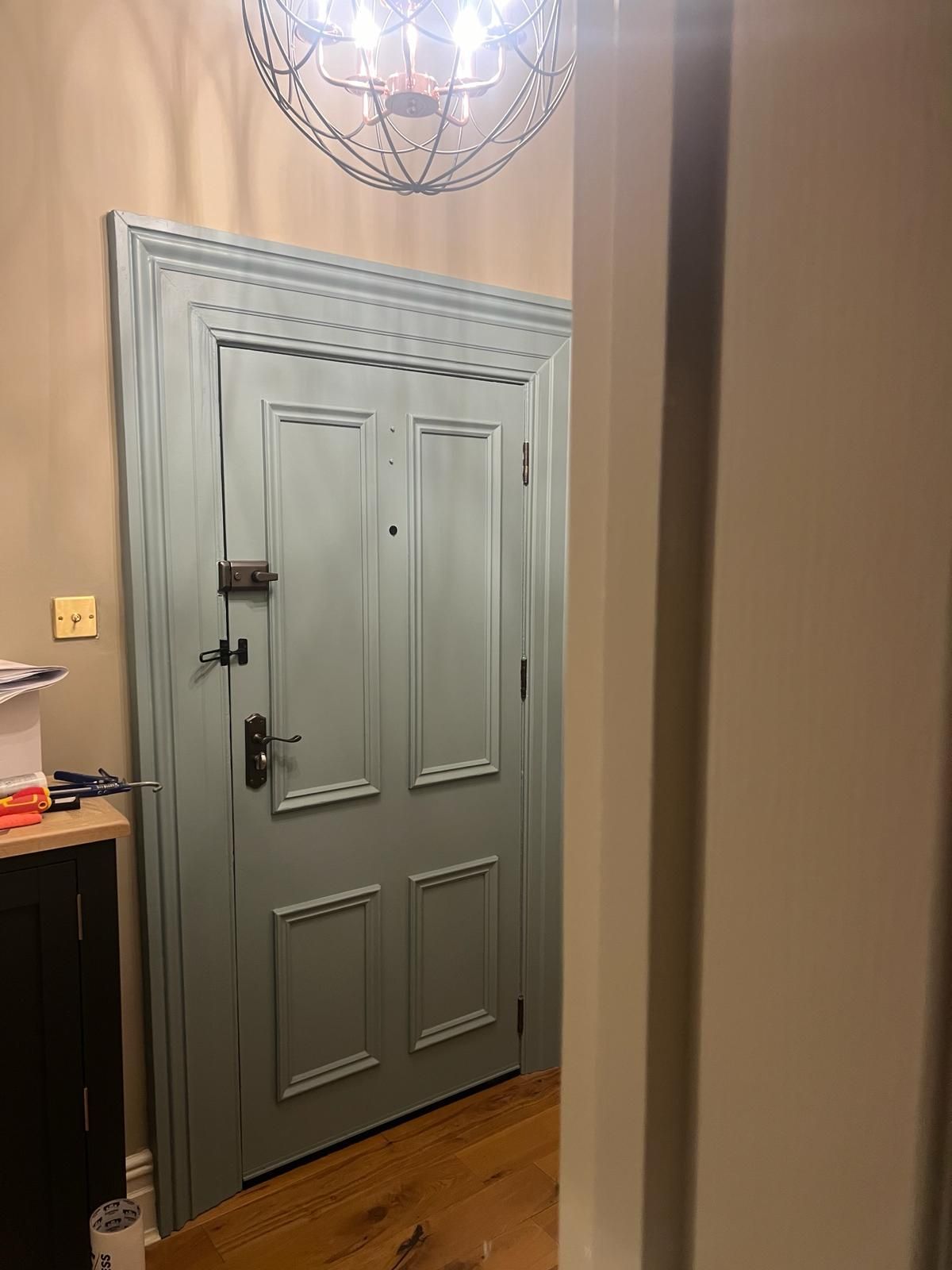 A blue door is sitting in a hallway next to a chandelier.