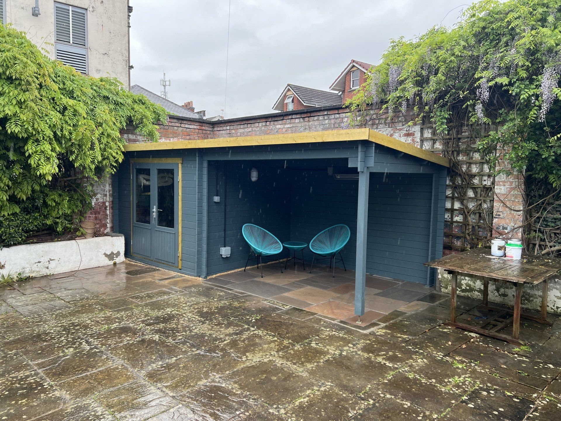 There are two chairs under a pergola in the backyard.