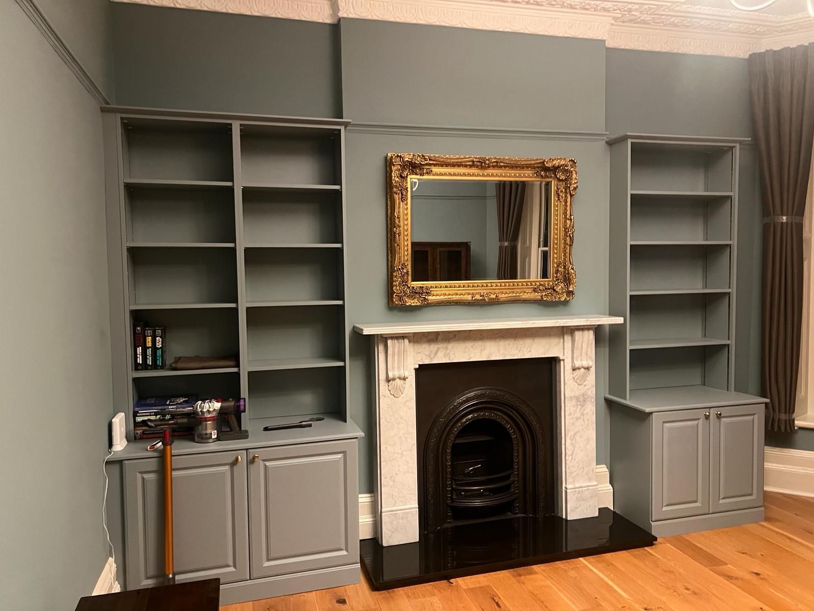 A living room with a fireplace , shelves , and a mirror.