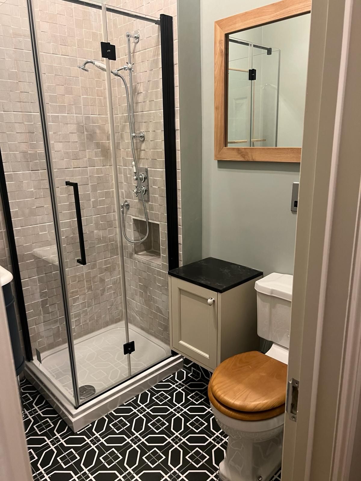 A bathroom with a toilet , shower and mirror.