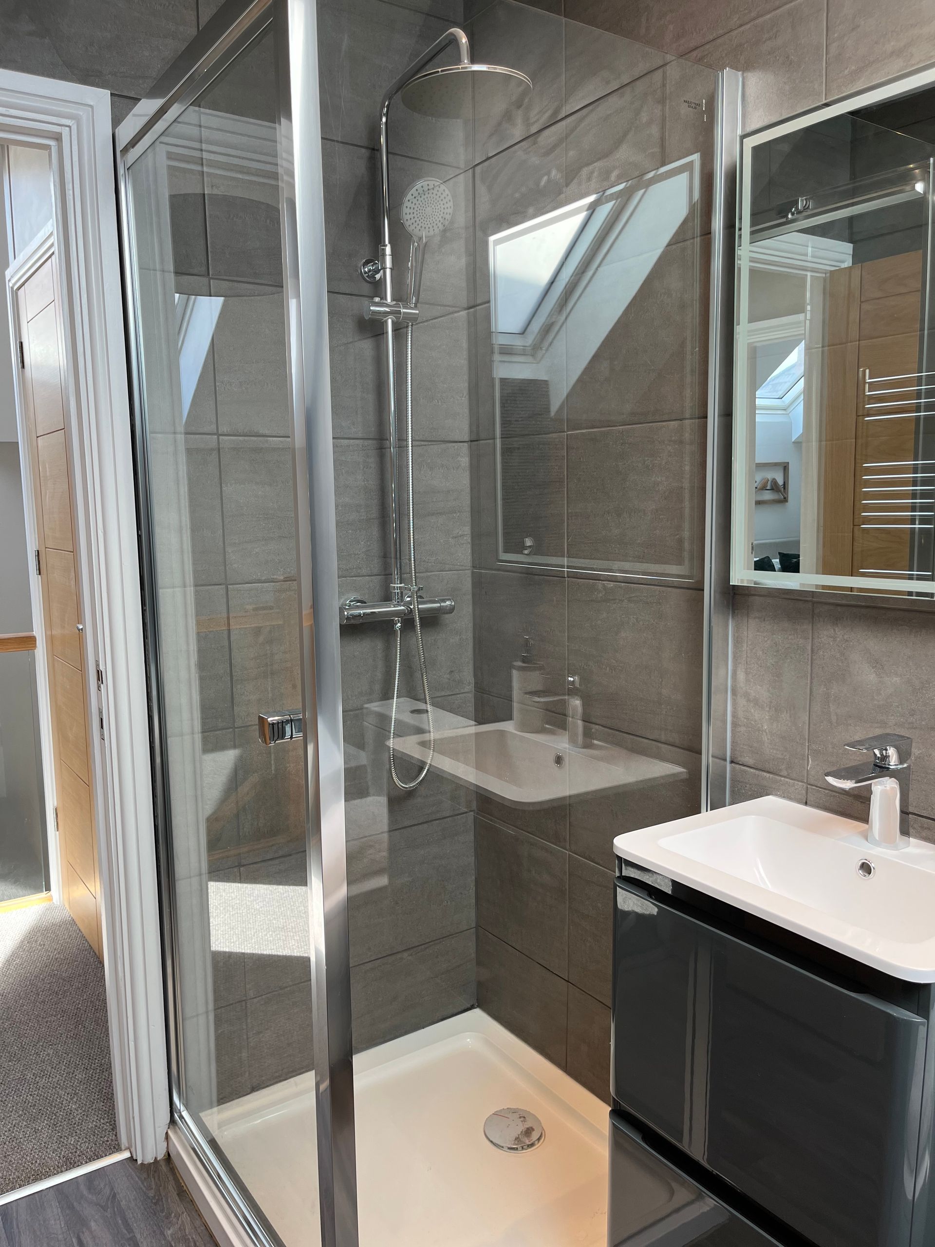 A bathroom with a walk in shower , sink and mirror.