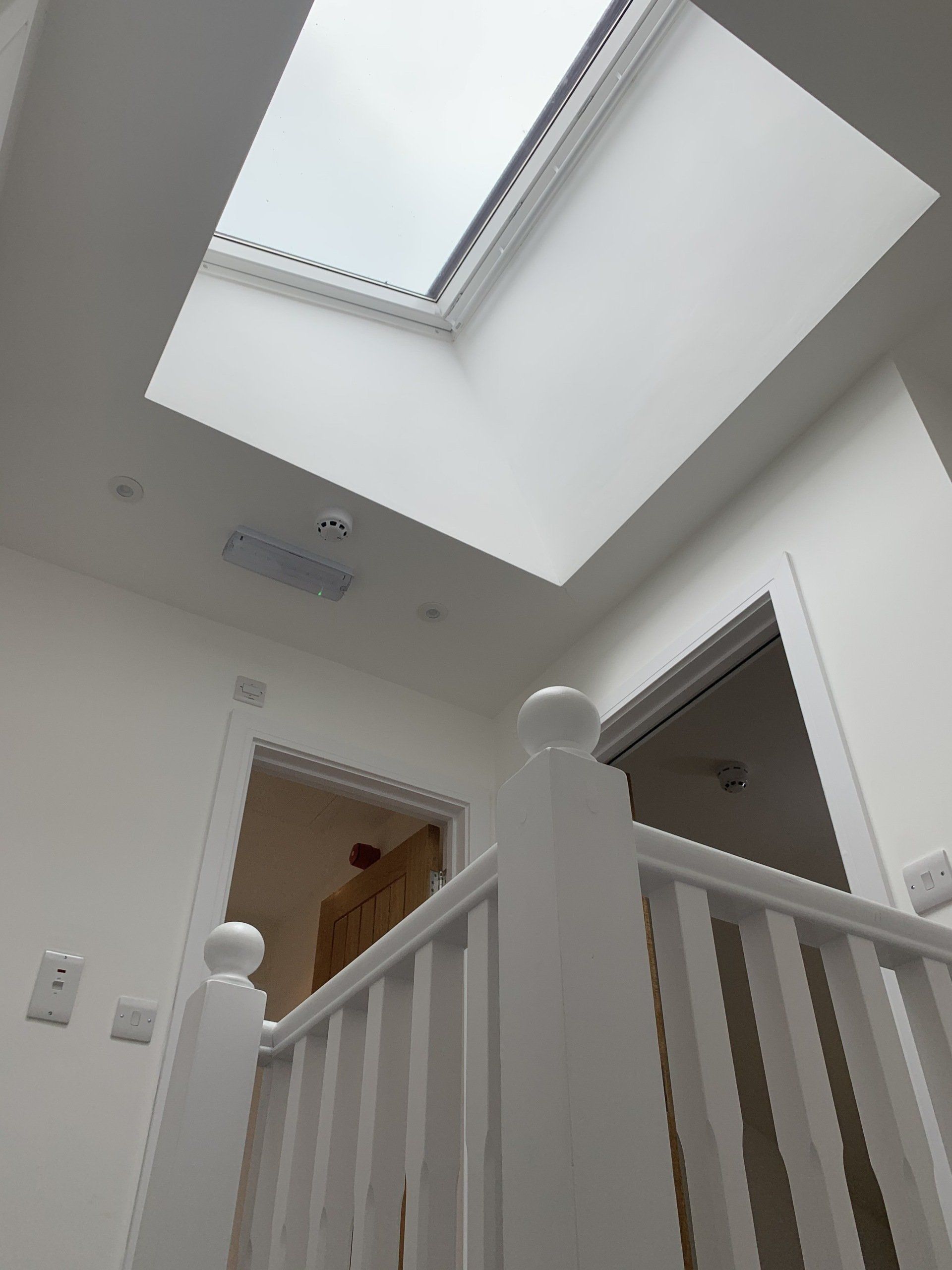 A white staircase with a skylight in the ceiling
