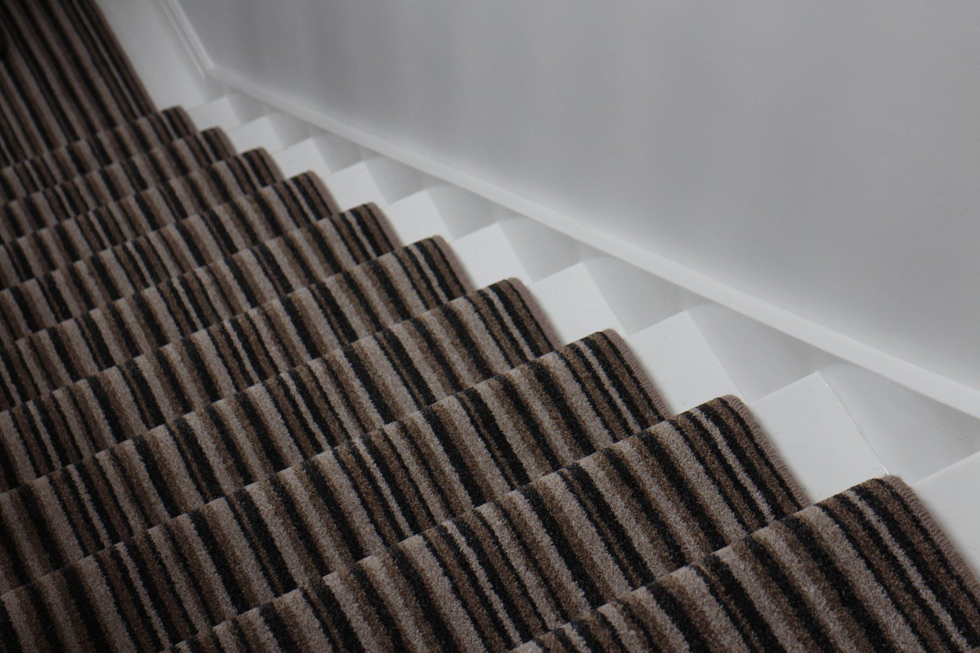 A close up of a staircase with a brown and black striped carpet.