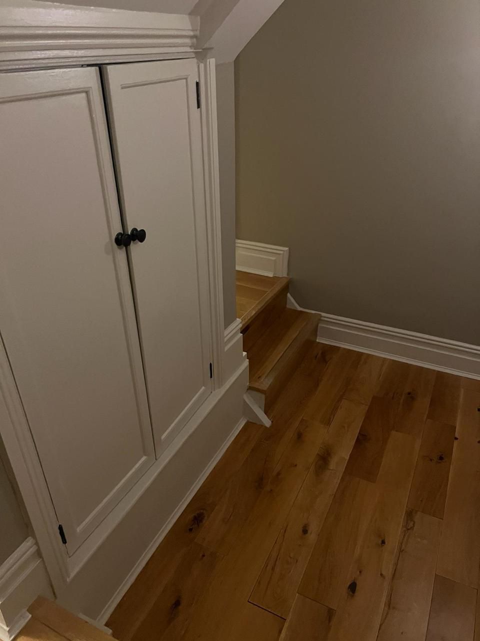 A room with hardwood floors and white cabinets