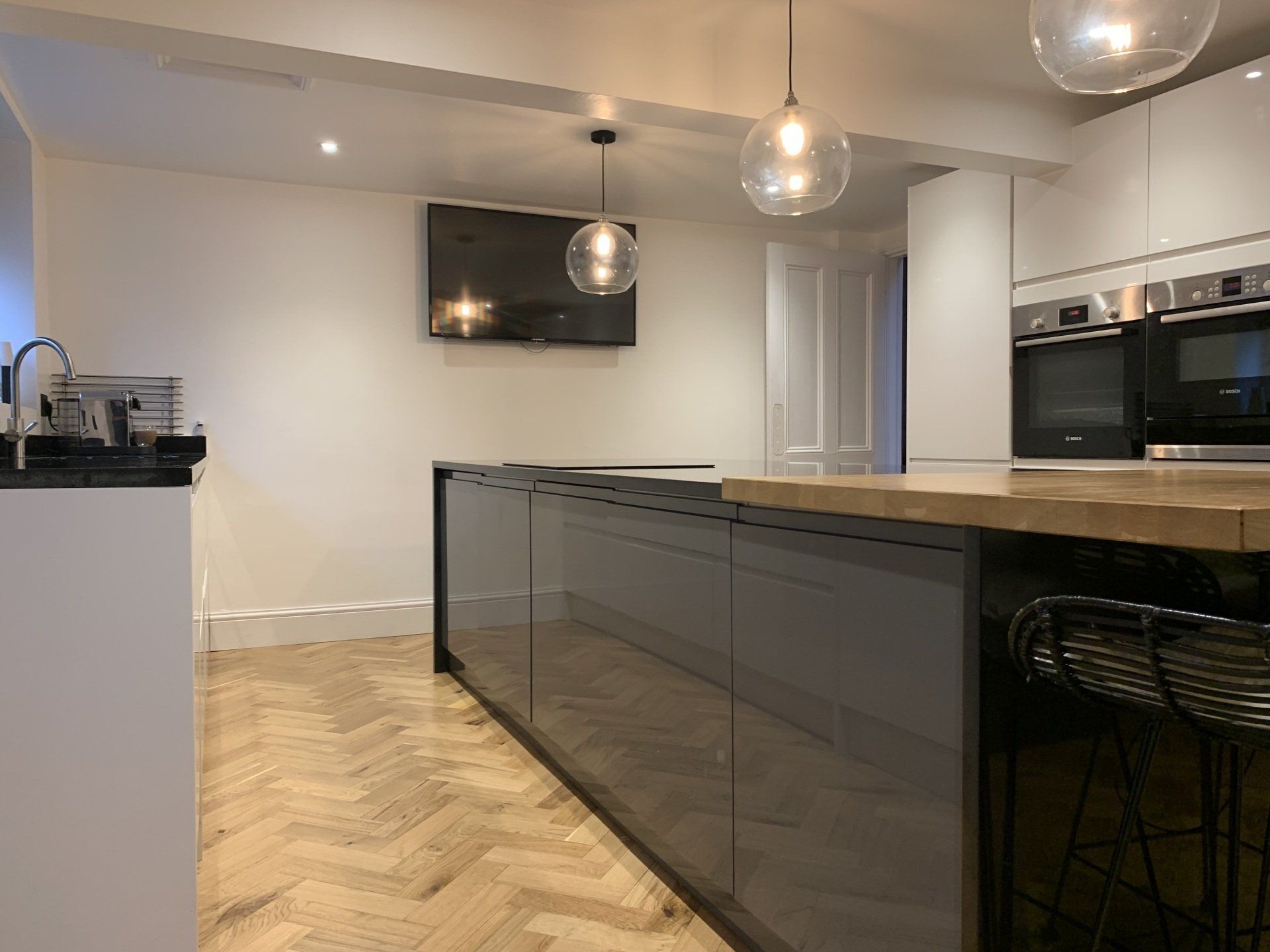 A kitchen with a large island and a flat screen tv on the wall.