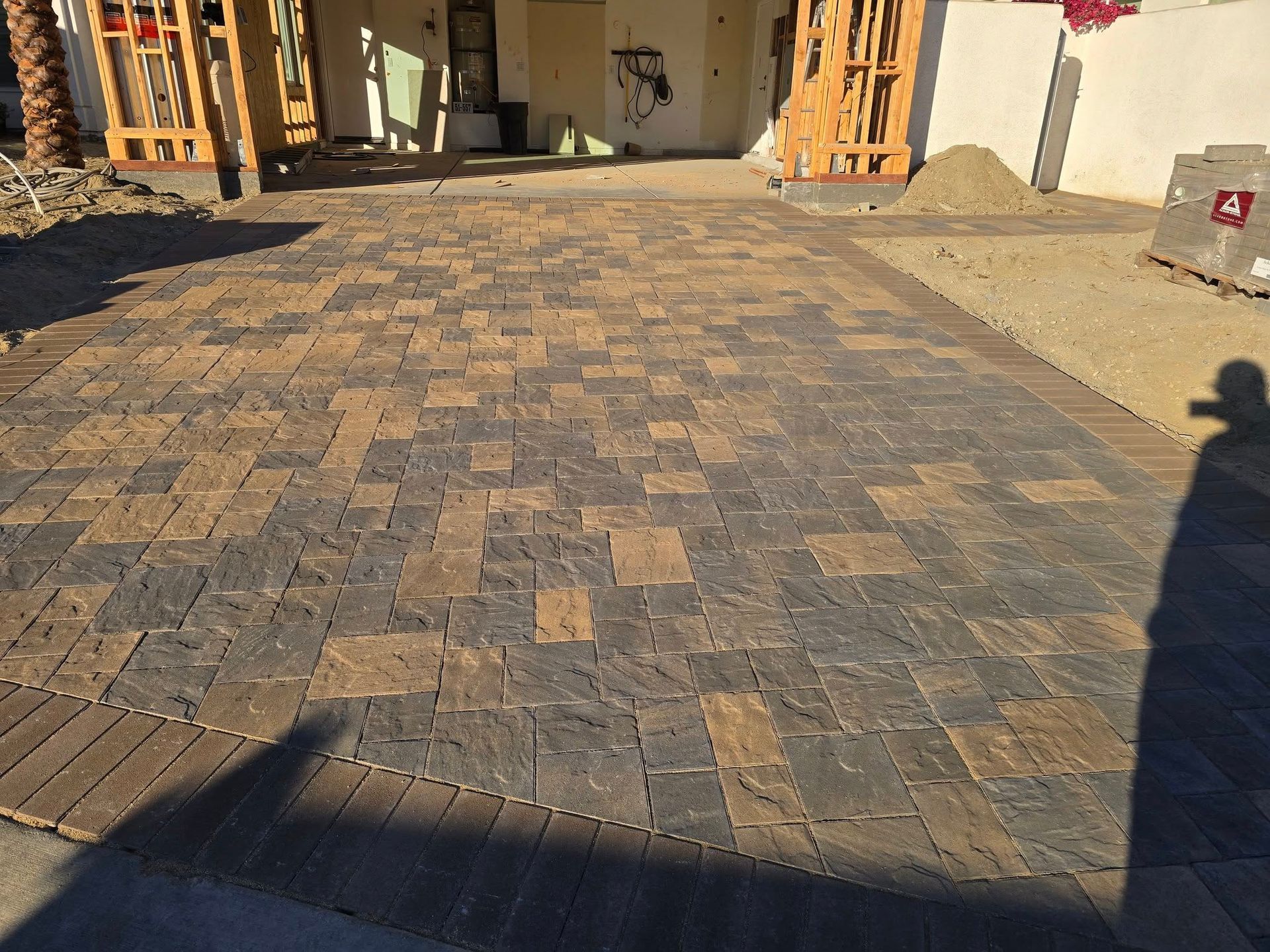 A brick driveway is being built in front of a house.