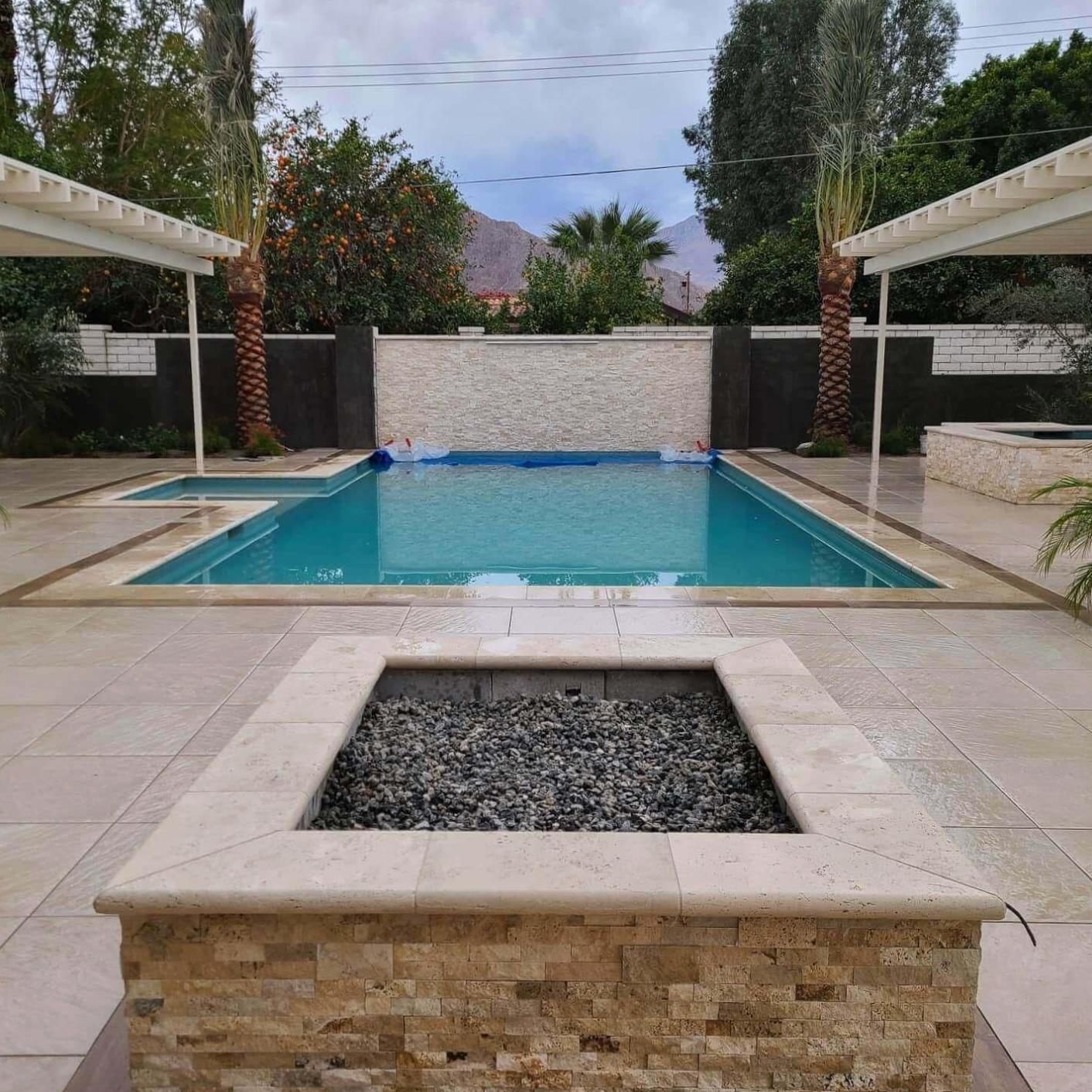 A large swimming pool with a fire pit in the middle of it