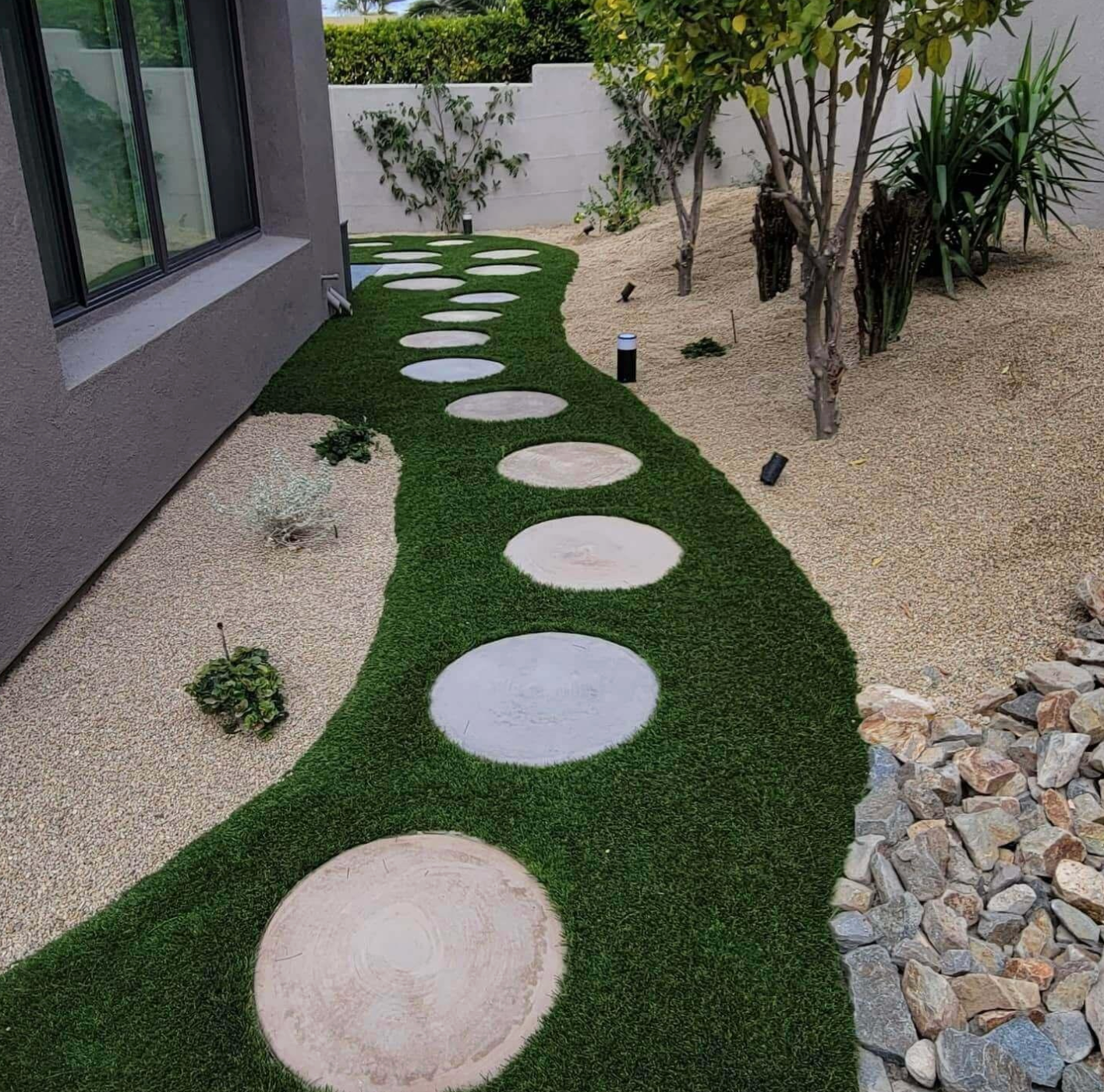 A walkway with stepping stones in the grass in front of a house.