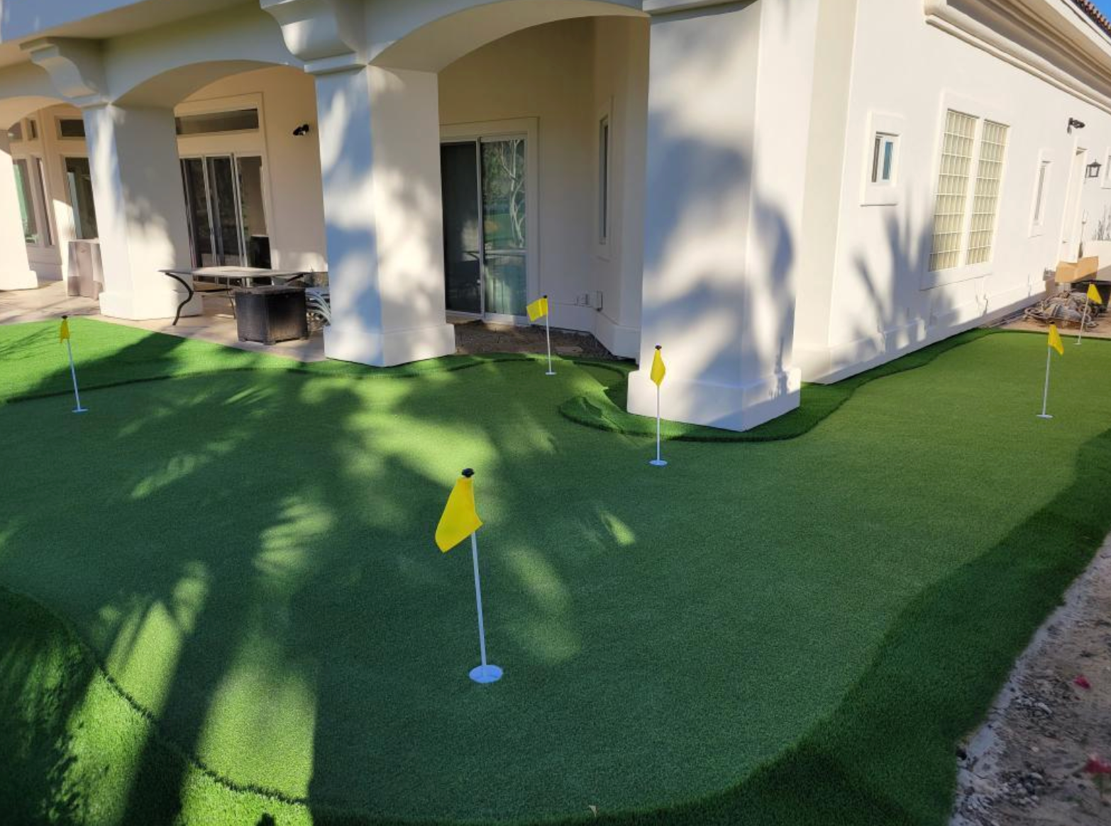 A white house with a putting green in front of it.