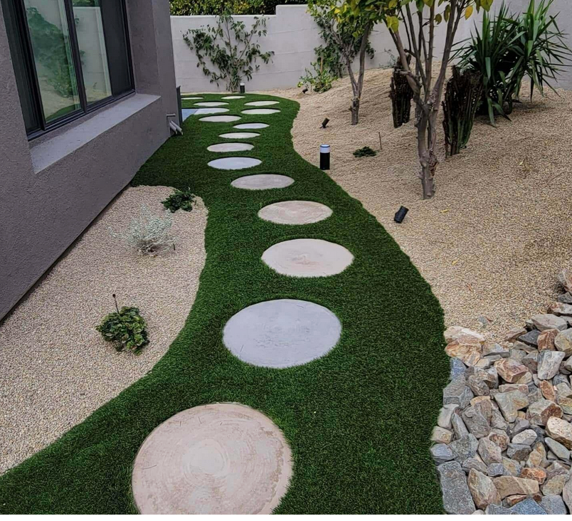 A path with circles in the grass leading to a house
