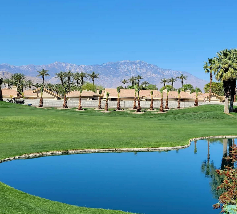 A golf course with palm trees and mountains in the background