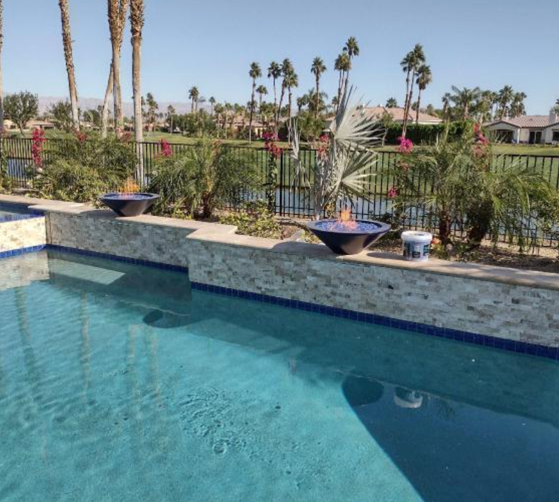 A swimming pool with a fence and palm trees in the background