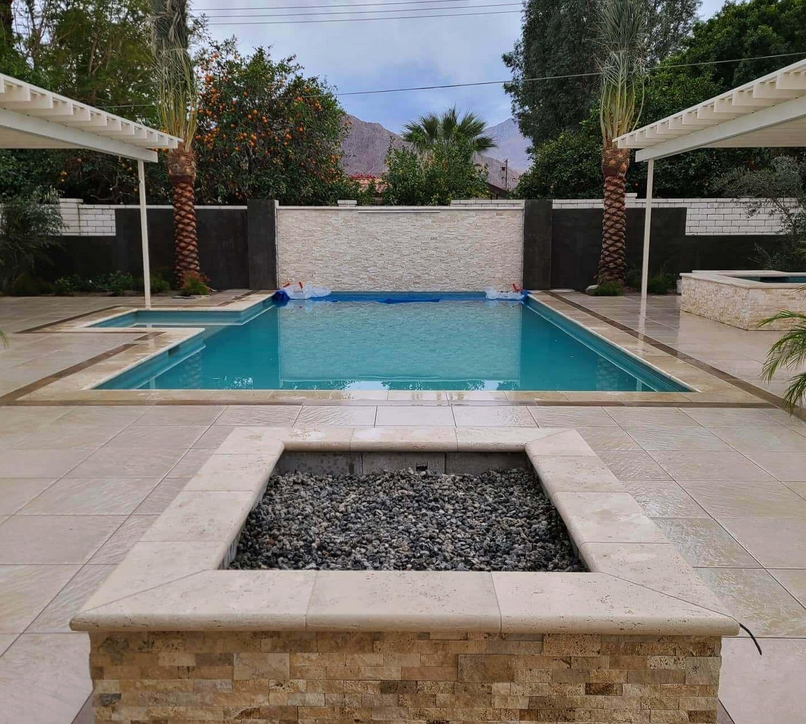 A large swimming pool with a fire pit in front of it