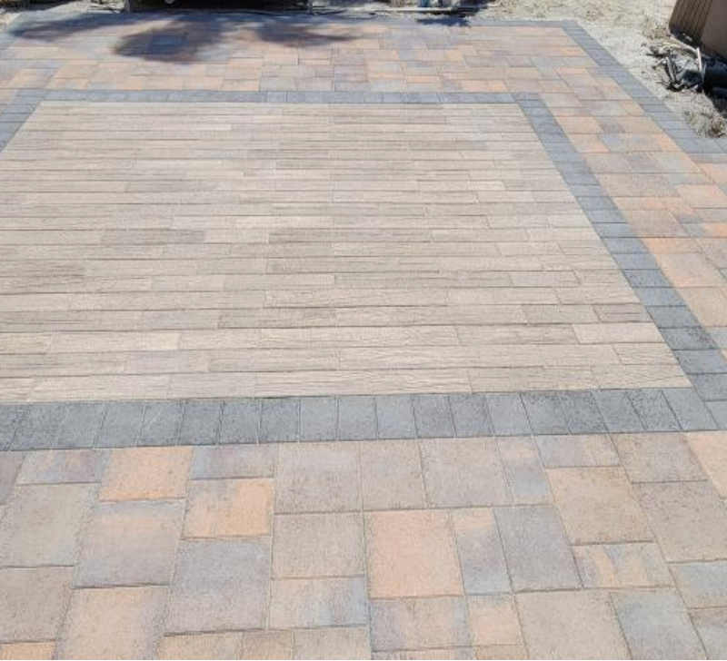 A brick driveway with a gray border and a wooden floor