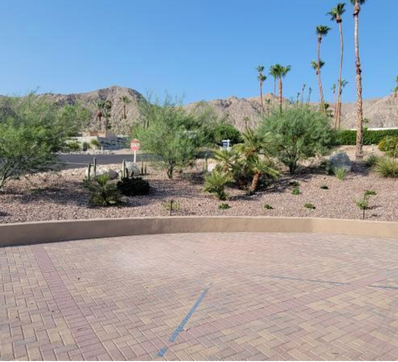 A parking lot with palm trees and mountains in the background