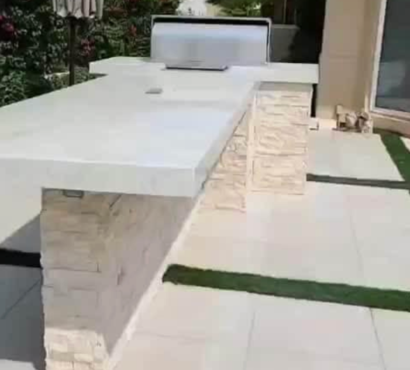 A patio with a table and a grill on it.