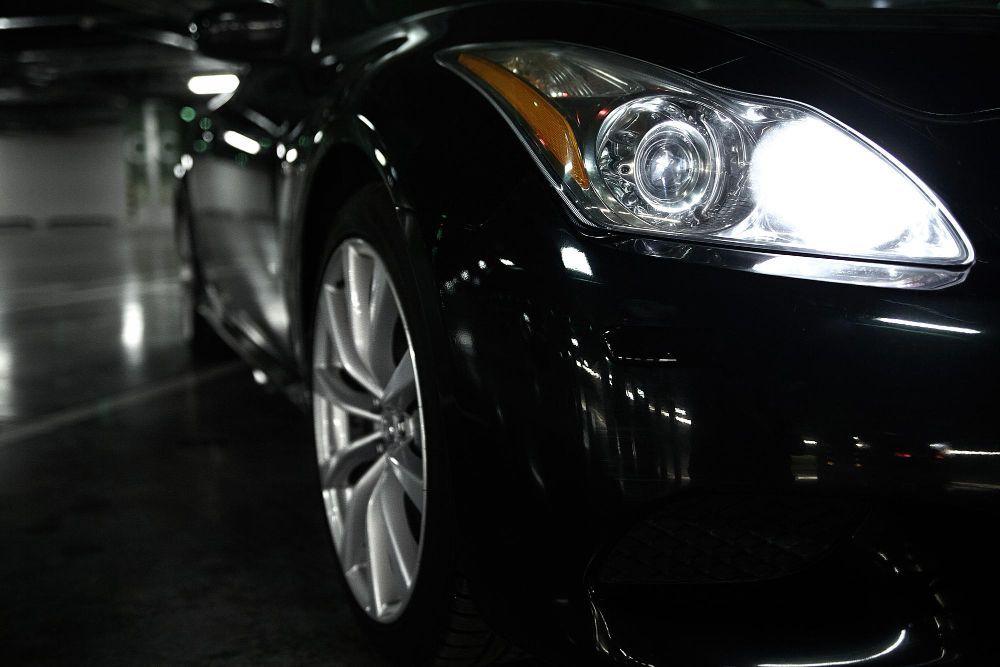 A black car is parked in a dark parking garage.