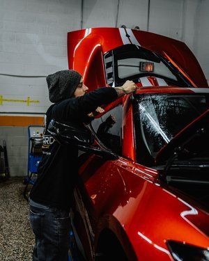 a man is working on a red sports car in a garage .
