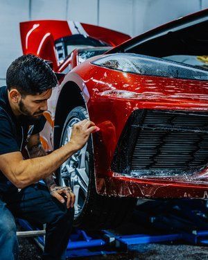 a man is working on a red sports car in a garage .