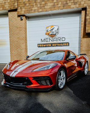 a red corvette is parked in front of a garage door .