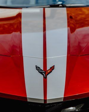 a red corvette with a white and red stripe on the hood .