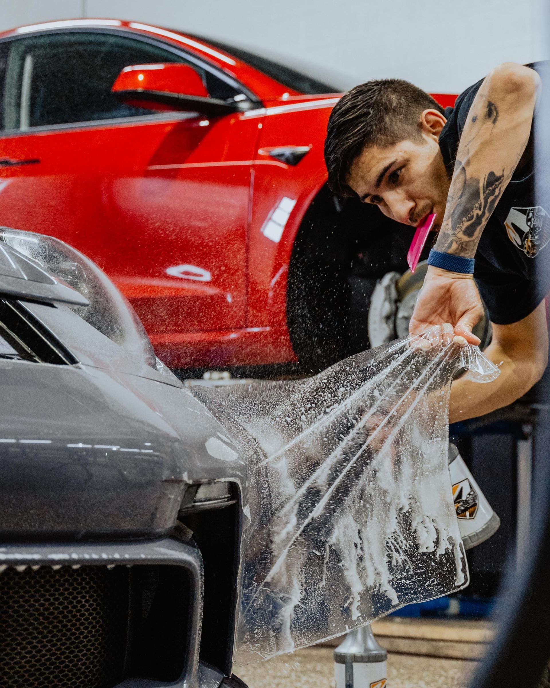 a man is wrapping a car with plastic wrap in a garage .ar pro