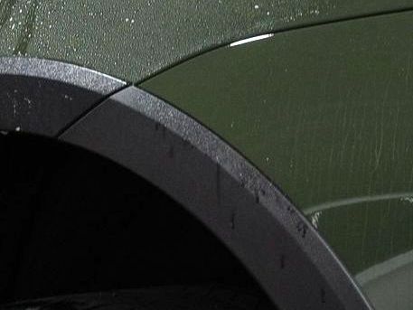 a close up of a car fender with water drops on it