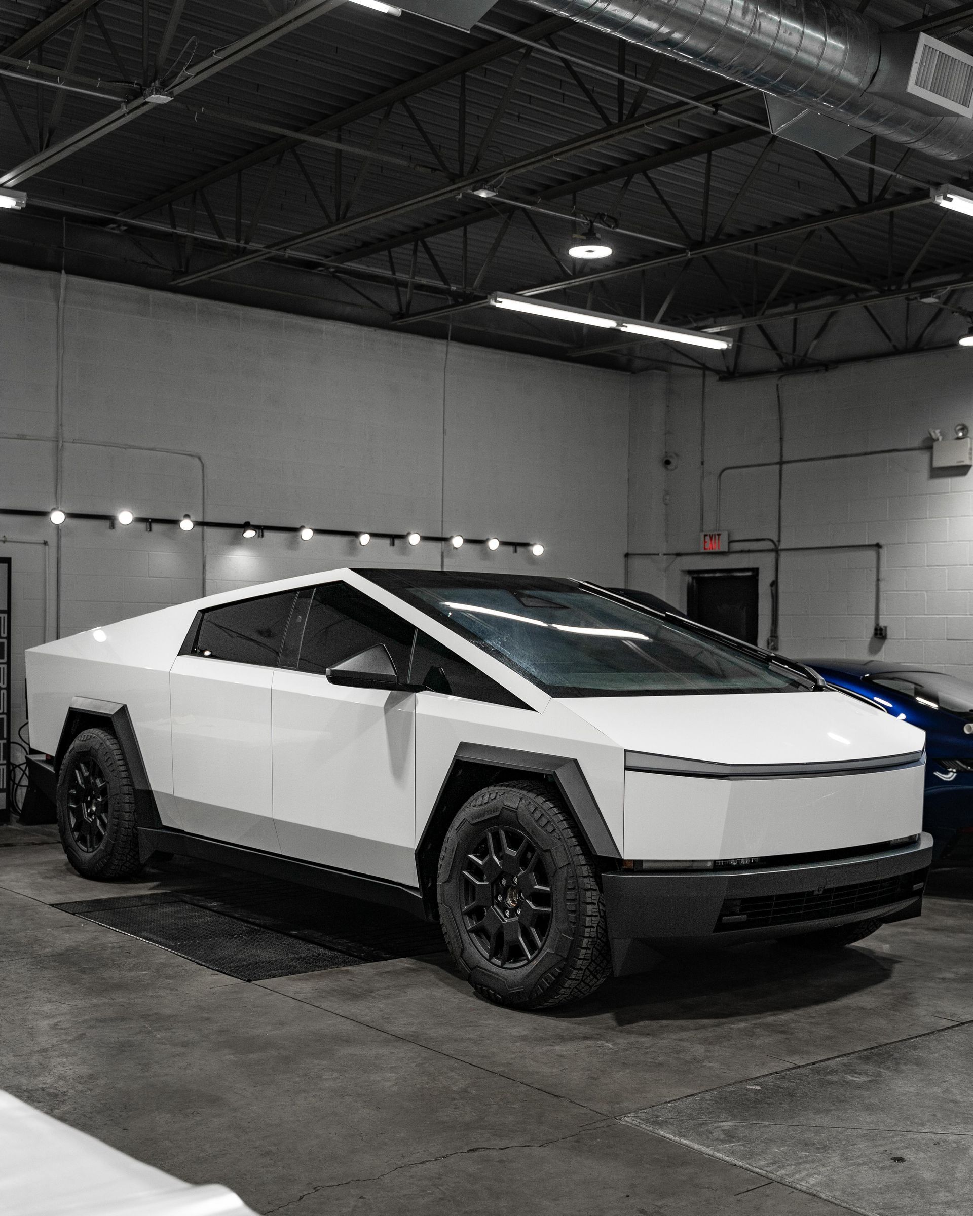A black tesla cybertruck is parked in a dirt field.