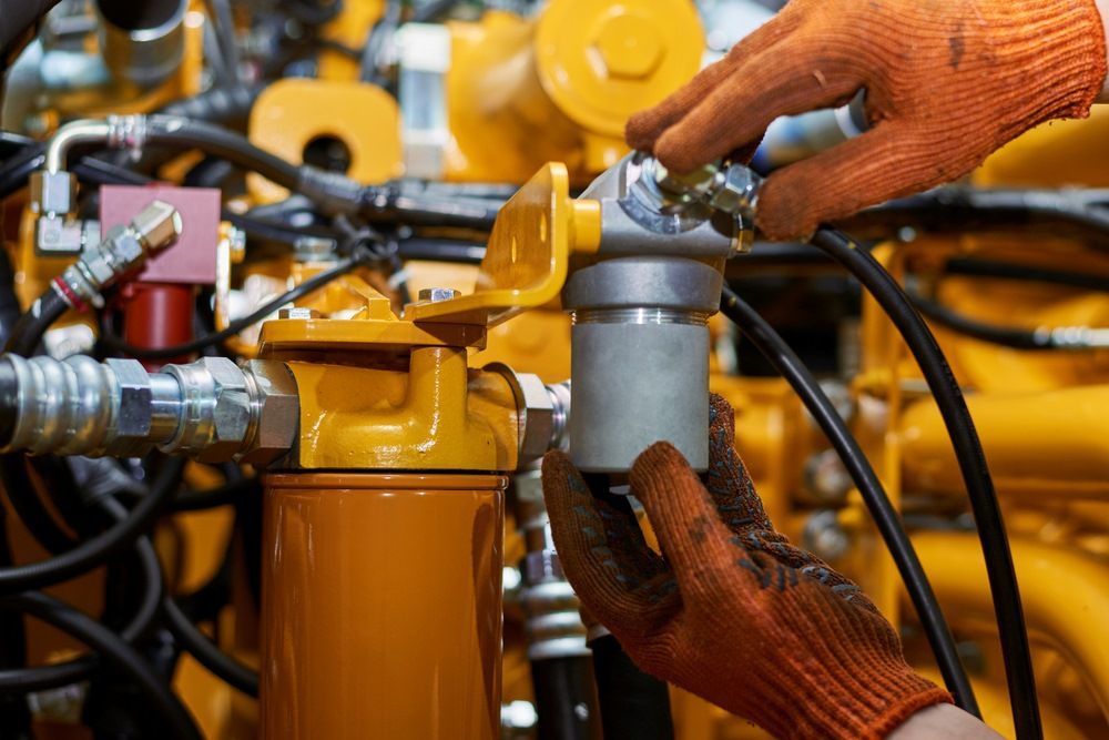 A Man Wearing Orange Gloves Is Working On A Yellow Engine — HI PSI Hydraulics in Wauchope, NSW