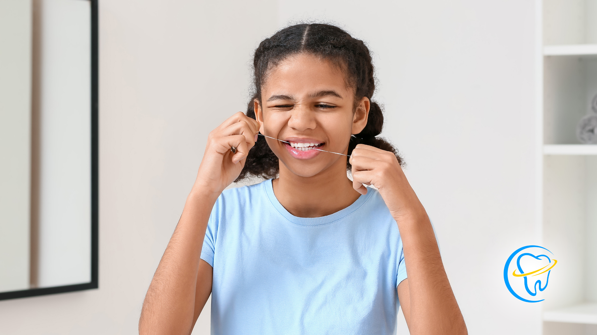 A young girl is flossing her teeth in front of a mirror.