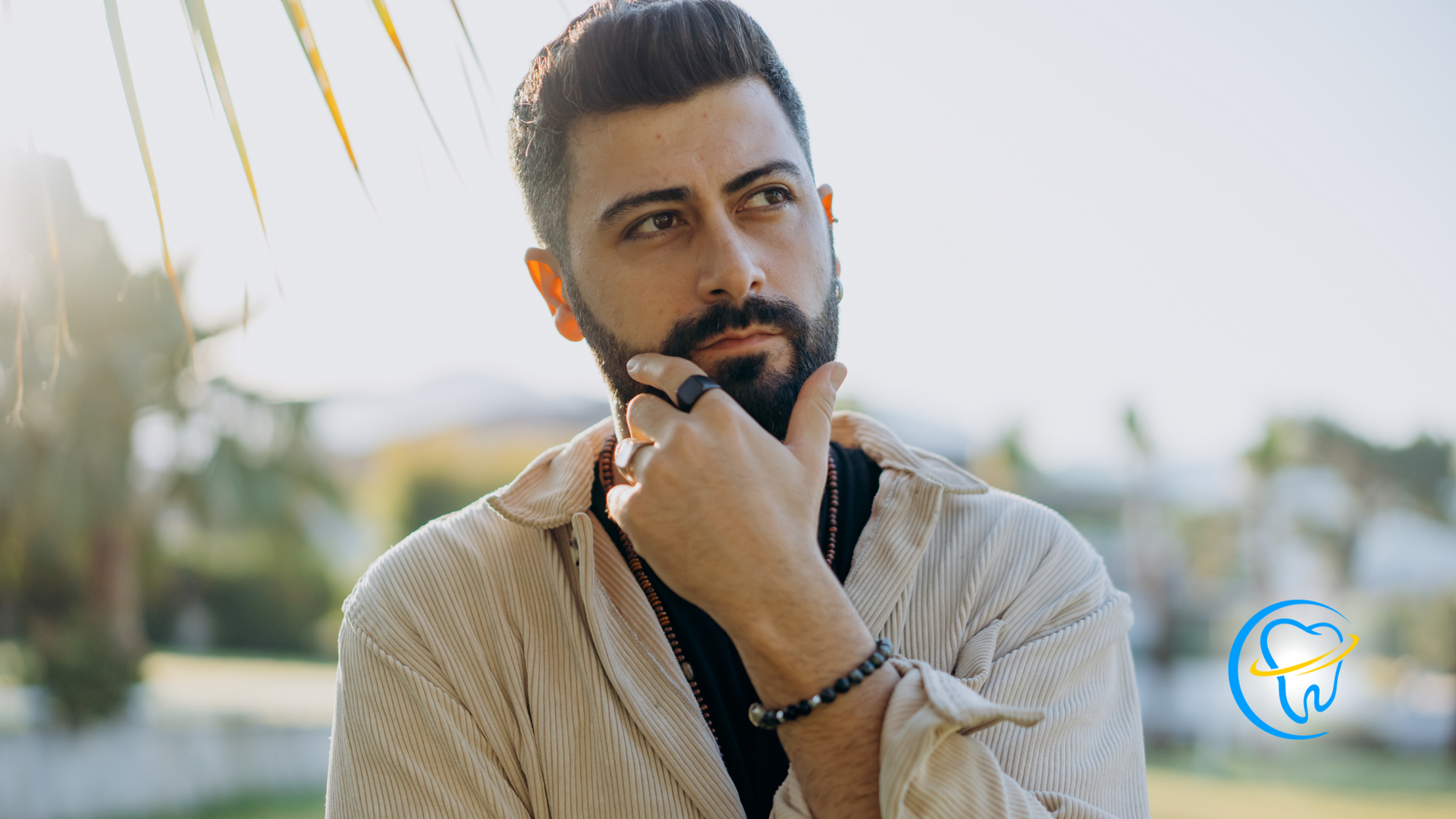A man with a beard is holding his hand to his chin.