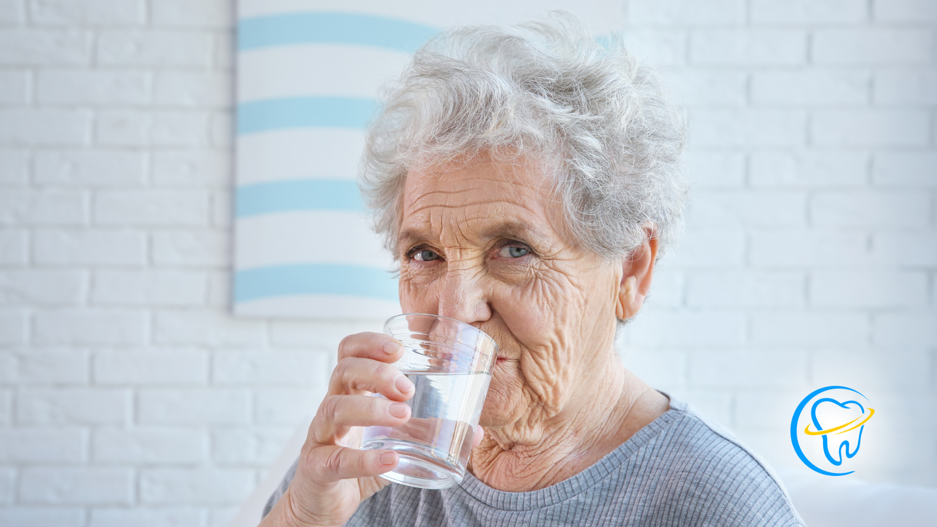 An elderly woman is drinking a glass of water.