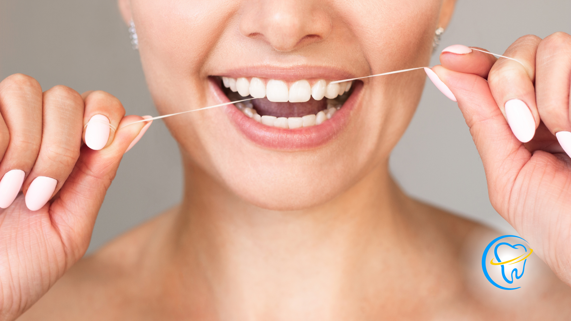 Woman flossing teeth; smiling with mouth open, holding floss taut.