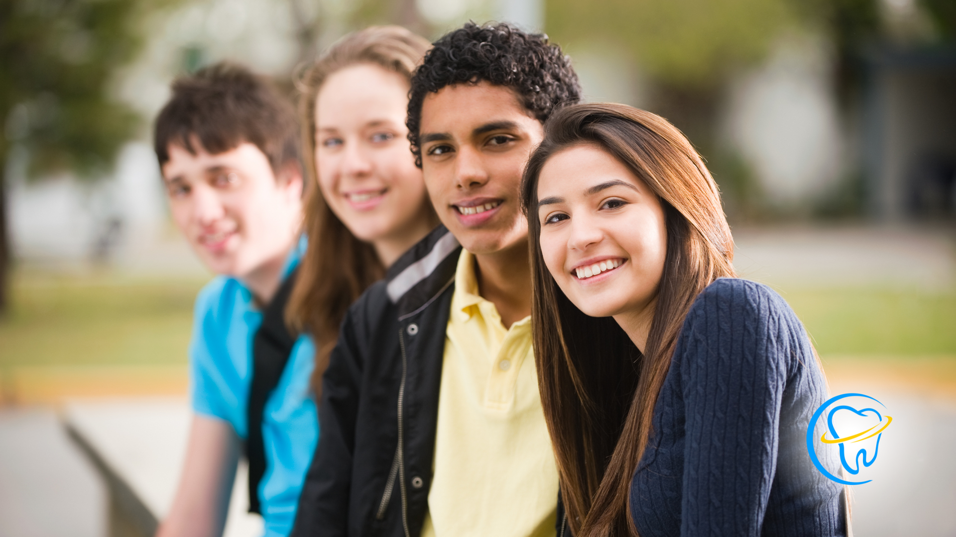 A group of young people are sitting next to each other and smiling for the camera.