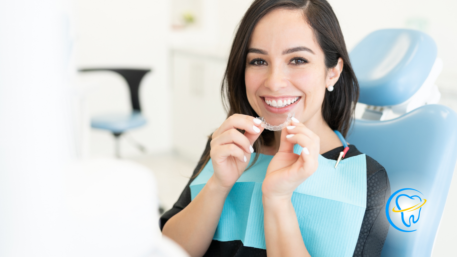 A woman is sitting in a dental chair holding a clear braces.