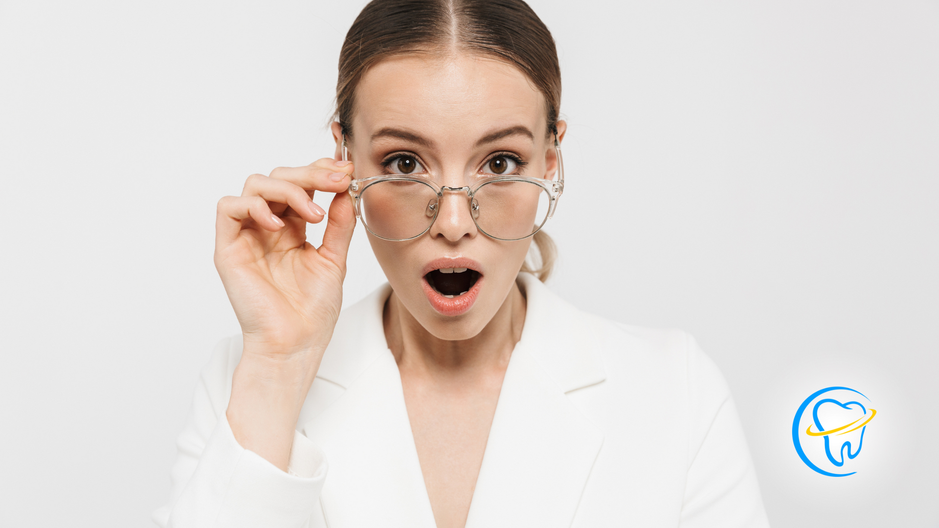 A woman wearing glasses and a white jacket is making a surprised face.