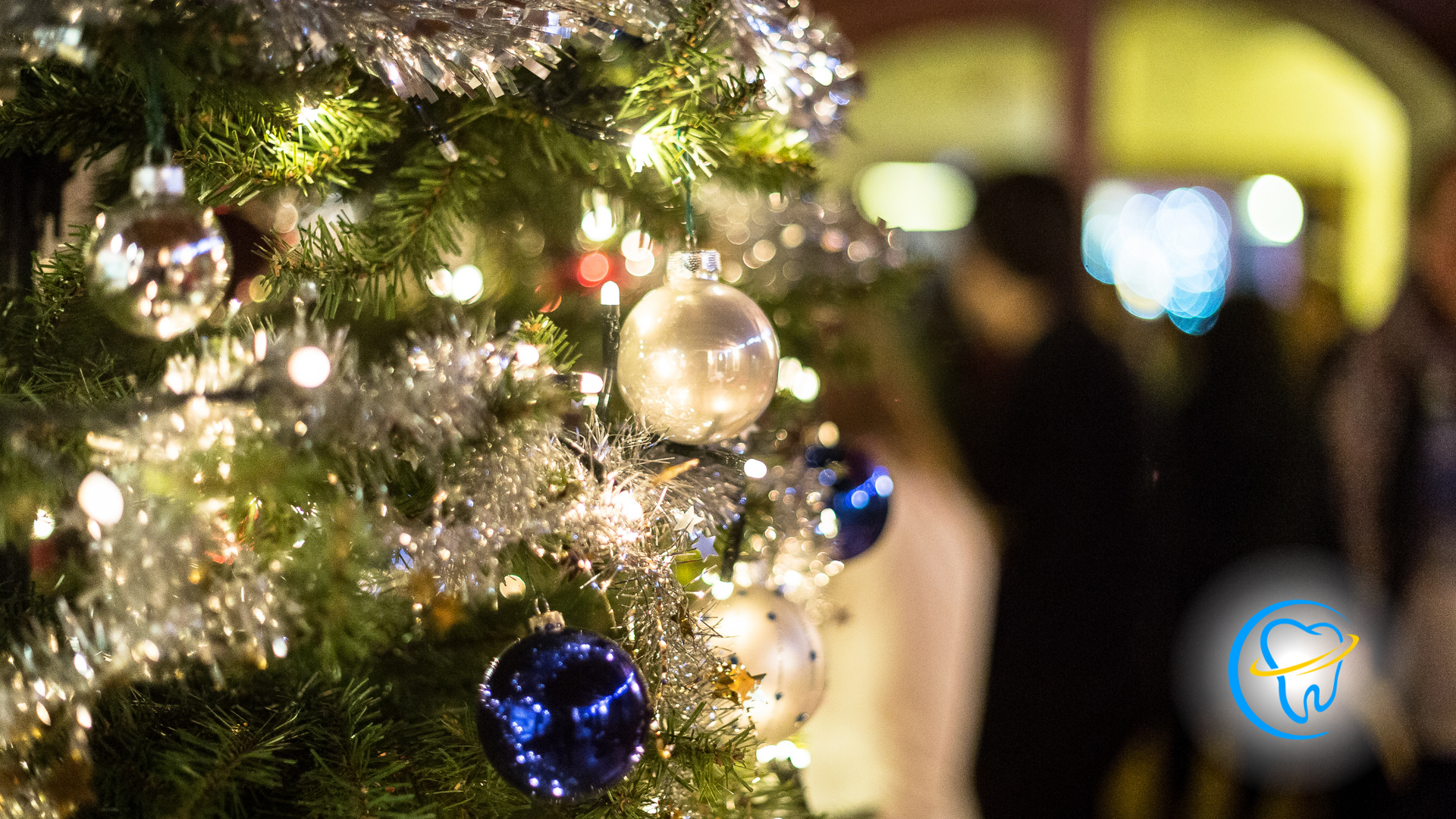A christmas tree is decorated with blue and silver ornaments and lights.