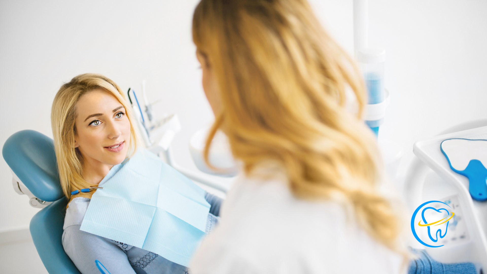A woman is sitting in a dental chair talking to a dentist.