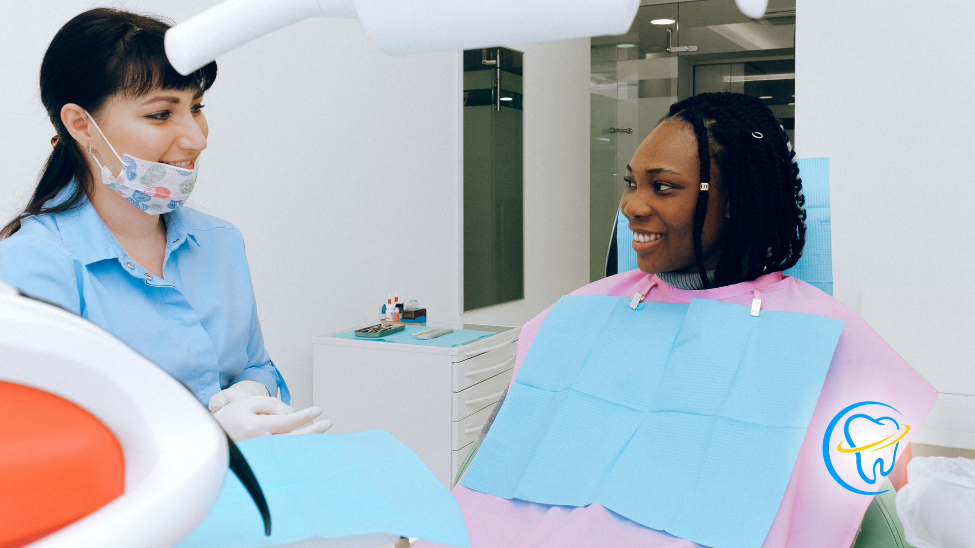 A woman is sitting in a dental chair talking to a dentist.
