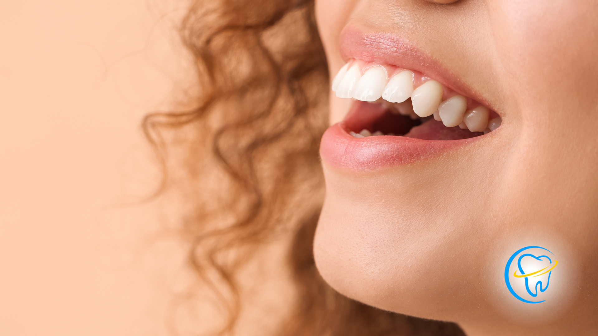 Close-up of a smiling mouth with white teeth against a peach background.