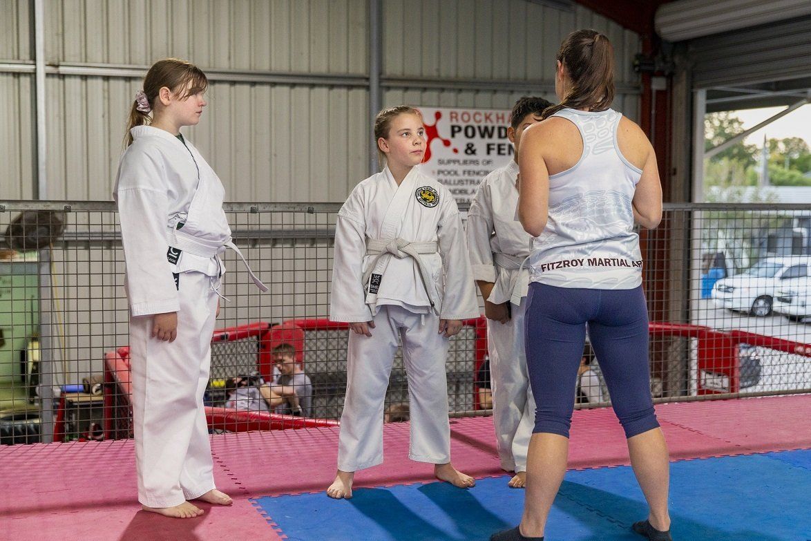 A group of people are standing on a mat in a gym talking to each other.