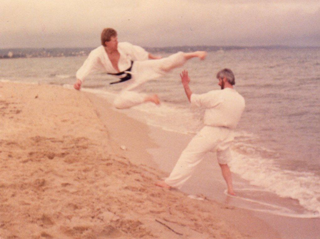Two men are practicing martial arts on the beach