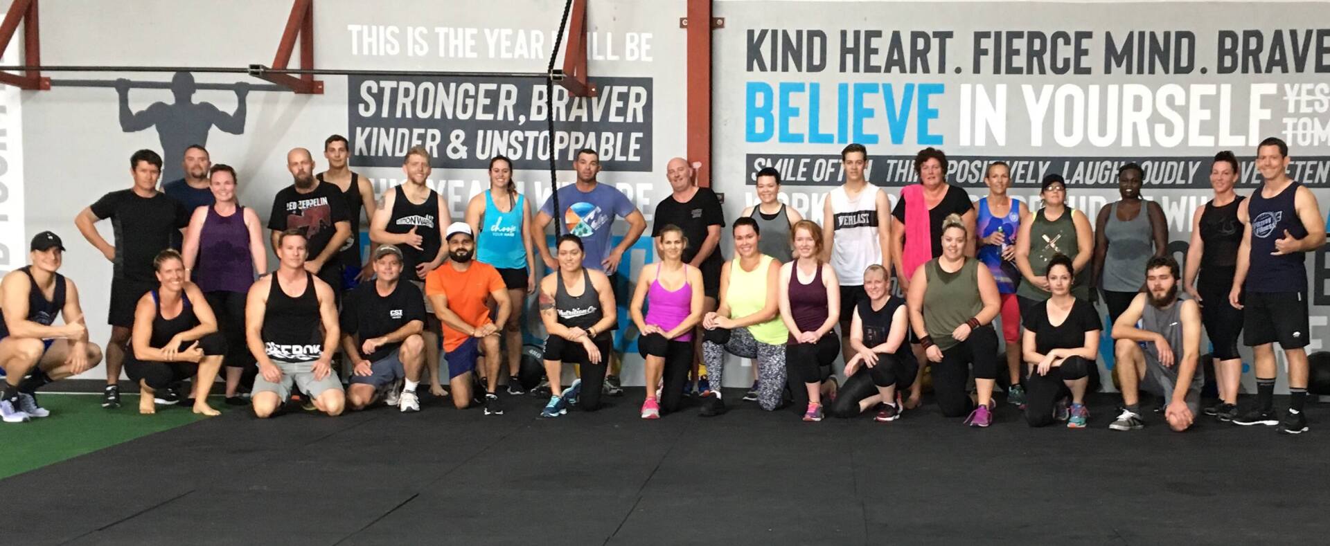 A group of people are posing for a picture in front of a sign that says kind heart fierce mind brave believe in yourself.